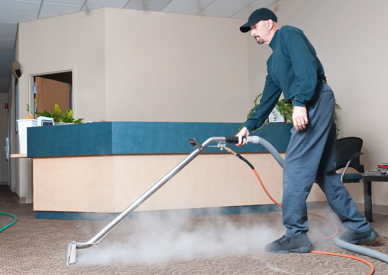 Man steam cleaning a carpet in an office lobby.