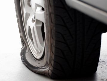 Close-up of a car's flat tire on a white floor.