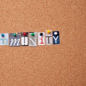 Letters pinned on corkboard spelling 'community'.