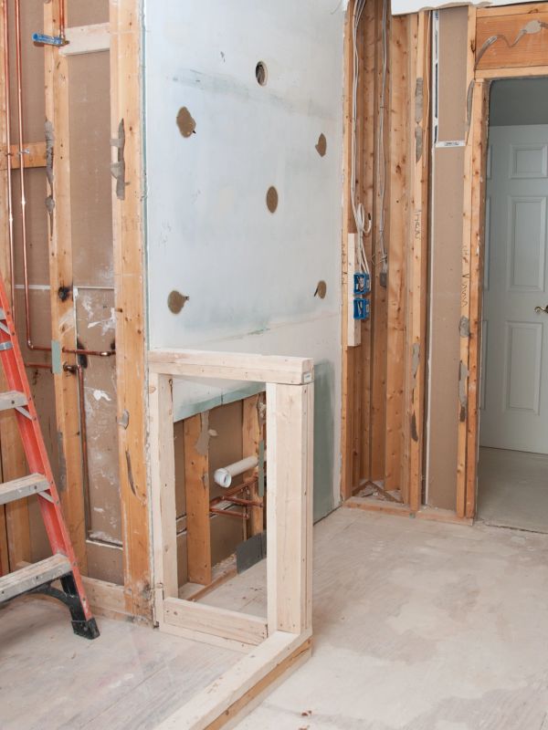 Room under renovation with exposed wooden framing and a ladder.