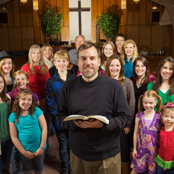 Group of smiling young adults wearing matching purple church youth group shirts.