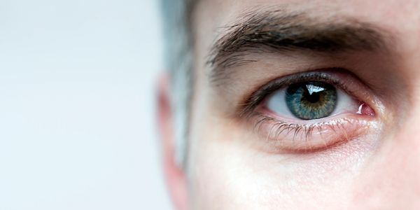 Close-up of a blue-green human eye with detailed iris and eyelashes.