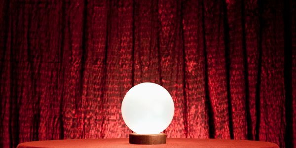 A glowing crystal ball on a red cloth-covered table with a red curtain background.