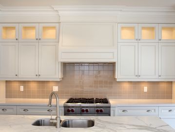 Modern kitchen with white cabinets and marble countertop.