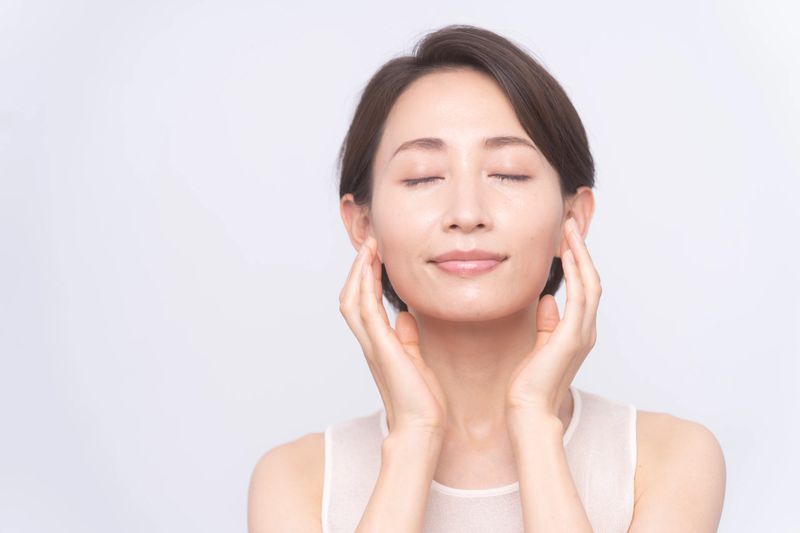 Skin care. An asian woman with beauty face is  touching healthy facial skin.