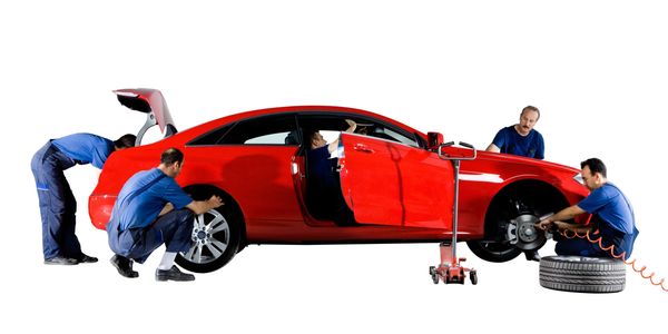 Team of mechanics working on a red car's tires and interior.