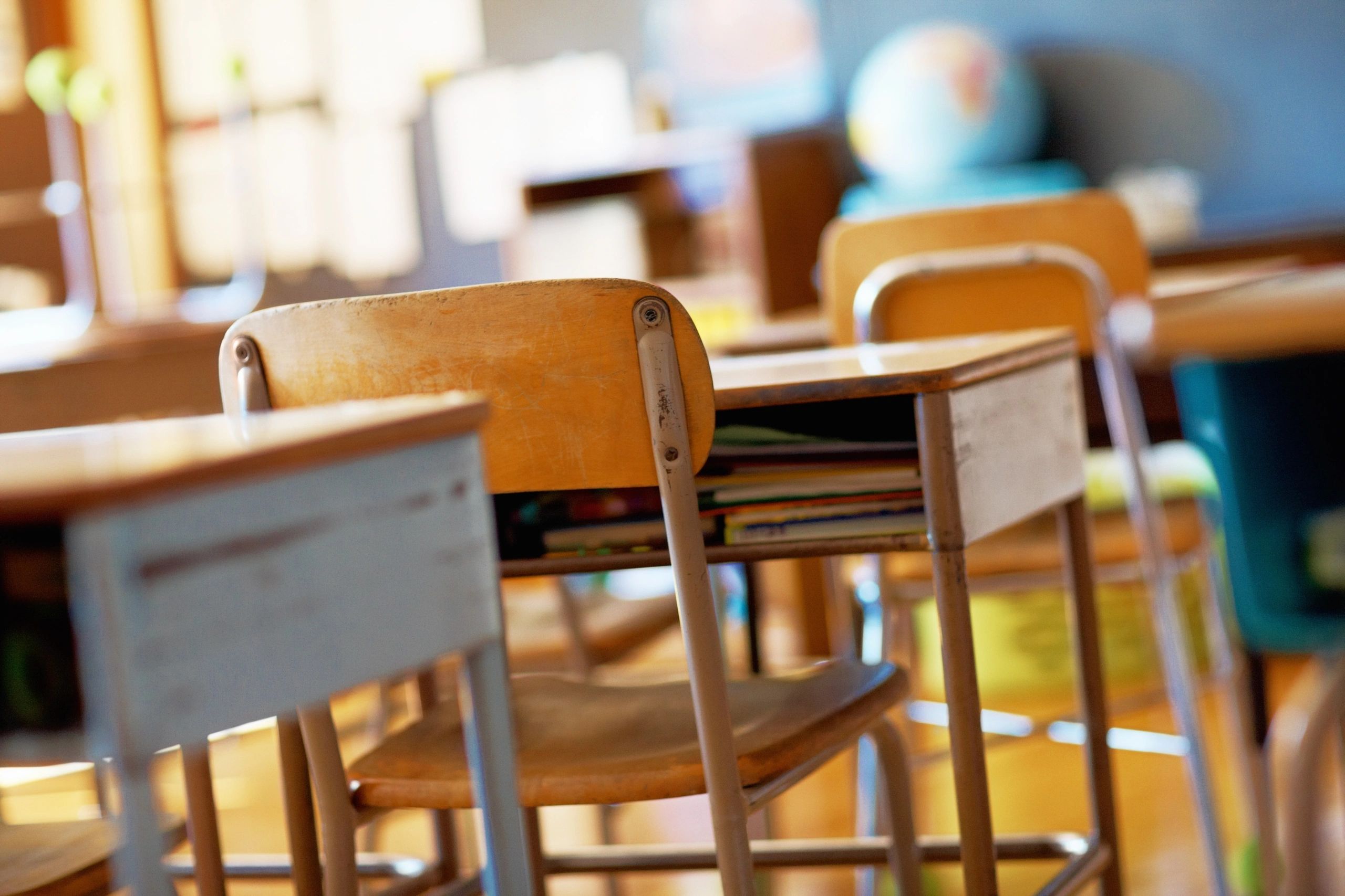 Empty classroom with wooden chairs and desks.