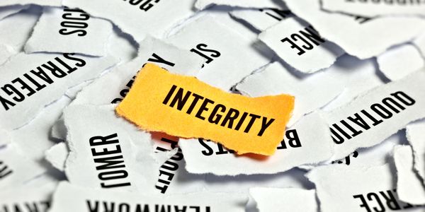 A torn paper with the word INTEGRITY stands out among scattered words.