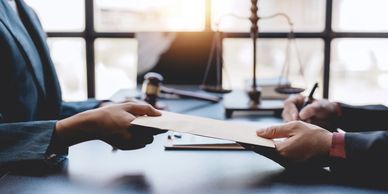 Two people exchanging a document in a legal office setting.