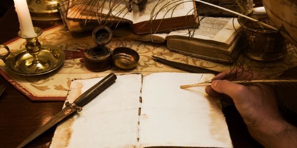 A hand writing on old parchment with a quill pen.