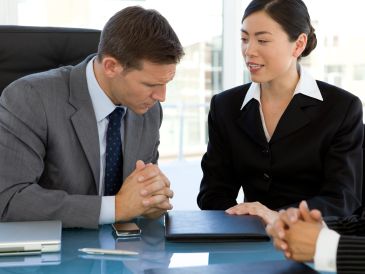 Two business professionals engaged in a discussion at a meeting.