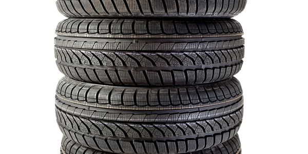 Stack of four black car tires with detailed treads on a white background.