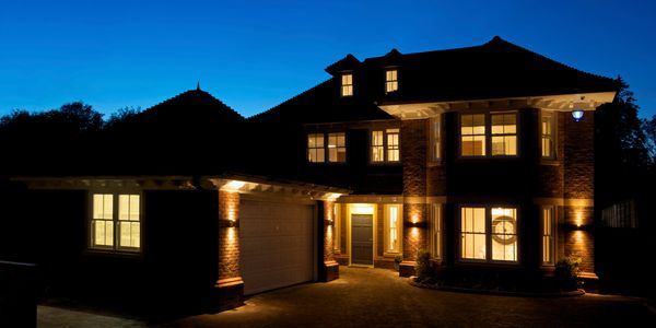 Illuminated two-story brick house with warm lights at dusk.