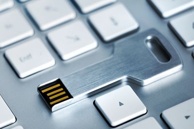 Metal key-shaped USB drive on keyboard.