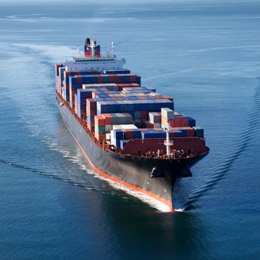 A large container ship carrying numerous cargo containers on calm blue waters.