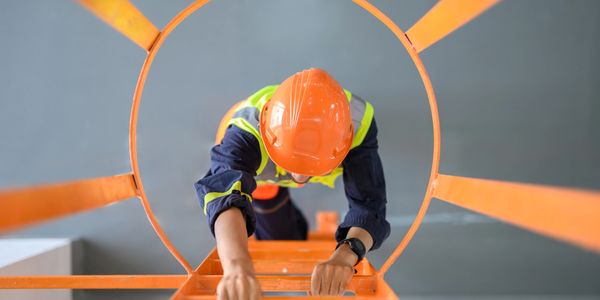 Travailleur isolé réalisant une intervention en hauteur dans un environnement industriel.