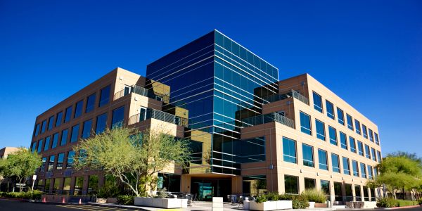 Modern office building with reflective glass windows under a clear blue sky.