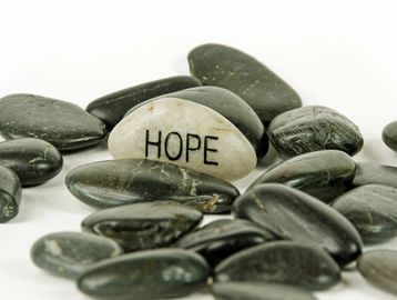 A white stone with "HOPE" written among black stones.