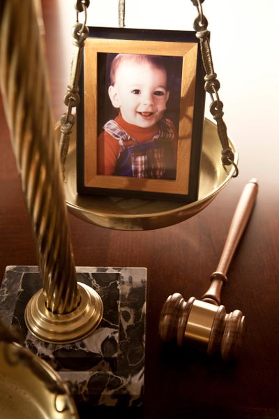A metallic justice scale on a wooden table in a courtroom.