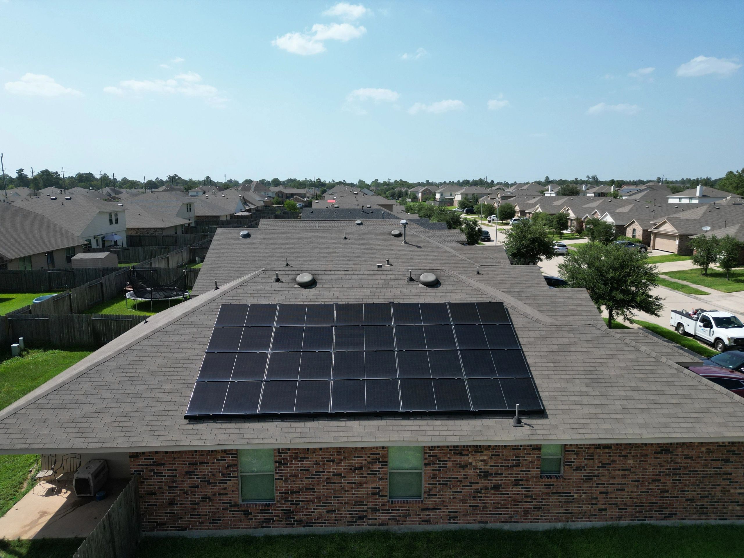 An aerial view of suburban homes in a residential neighborhood with solar panels on rooftop