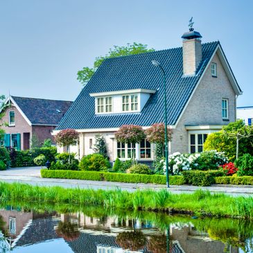 A charming house with a blue roof beside a reflective water canal.