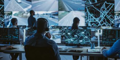 People monitoring traffic on multiple screens in a control room.