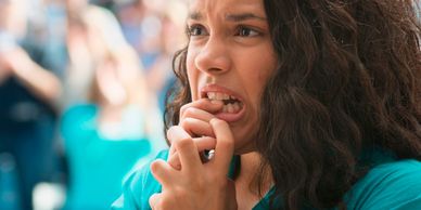 Worried woman biting her nails, showing anxiety.