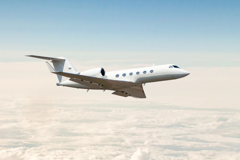 White luxury business jet flying in the air above the clouds
