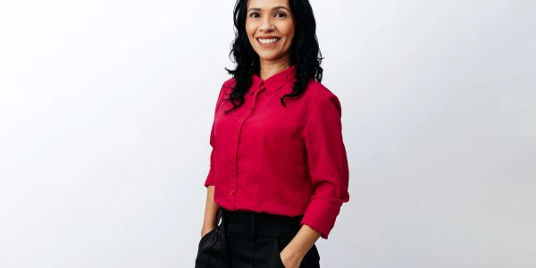 Smiling woman in red blouse and black pants.