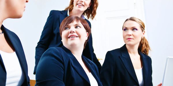 Four professional women in black blazers having a business meeting.