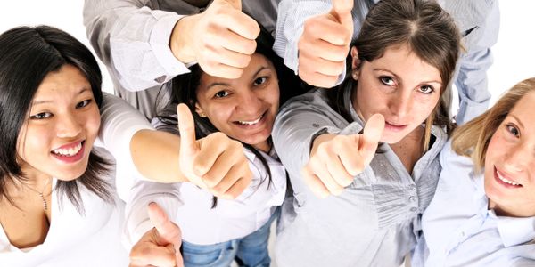 A diverse group of young adults giving thumbs up and smiling.