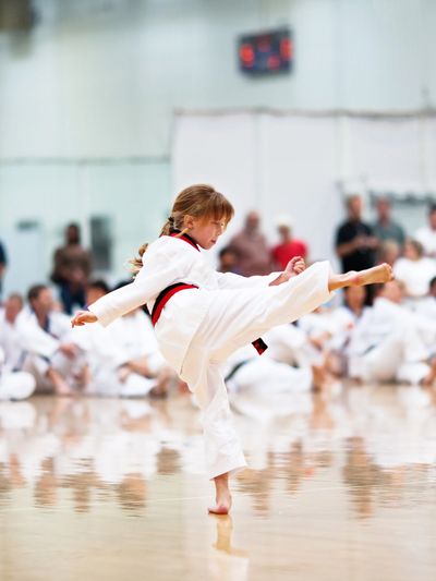 Young girl practicing martial arts kick in gym.