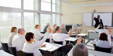 Adults raising hands in a classroom.