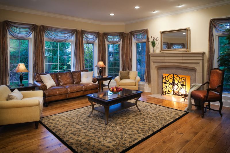Lovely stylish well appointed living room with burning fireplace, elegant curtains and hardwood floors.