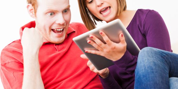 A couple excitedly looking at a tablet together.