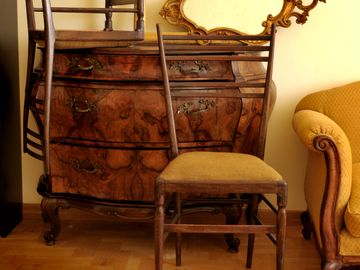 Vintage wooden furniture with an ornate mirror and upholstered yellow chair.
