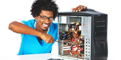 Man fixing a desktop computer with a screwdriver.
