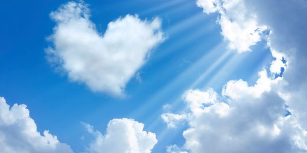 Heart-shaped cloud in bright blue sky.