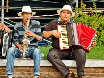 Two men playing accordion and saxophone outdoors.