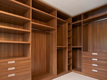Empty wooden closet with shelves and drawers.