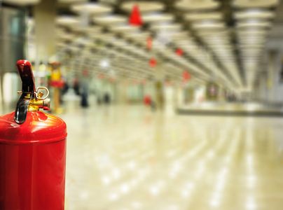A red fire extinguisher in a spacious, well-lit corridor.