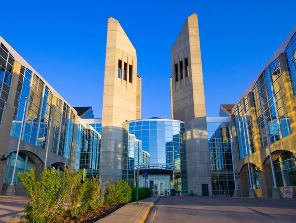 Modern building with two tall towers and glass facade under clear blue sky.