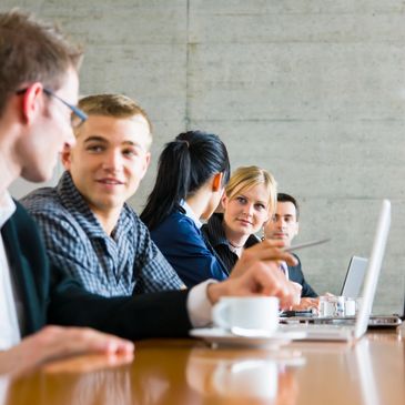 Colleagues engaged in a discussion during a meeting around a conference table.