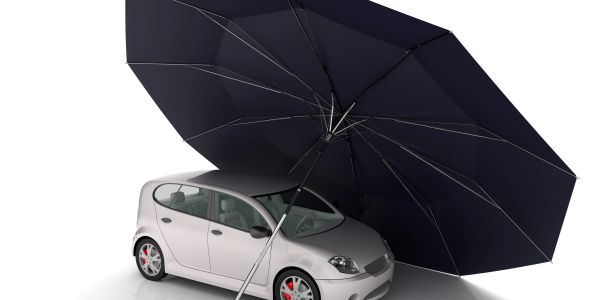 A car sheltered under a large umbrella.