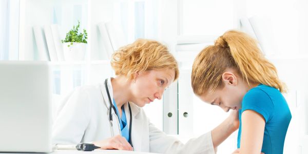 Doctor comforting a young girl in a medical office.