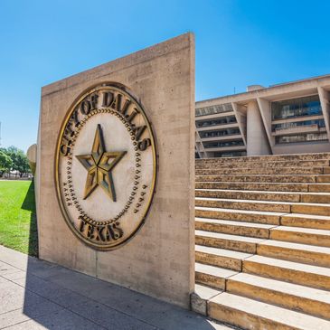 The City of Dallas emblem displayed on a concrete wall near steps.