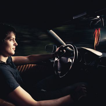 Young man driving a car at night, focused on the road.
