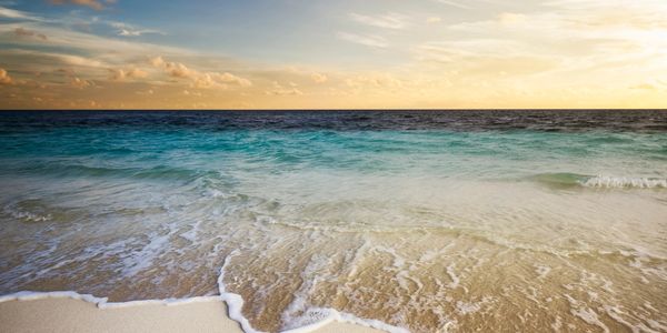 The year 2013 written in sand on a beach with waves approaching.