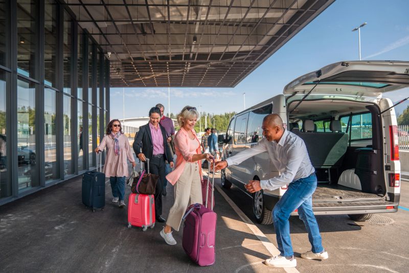 Mid adult Hispanic male airport shuttle driver loading costumers luggage in to the van.