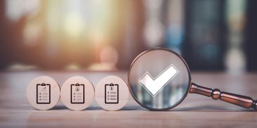 Magnifying glass highlighting a check mark among checklist icons.